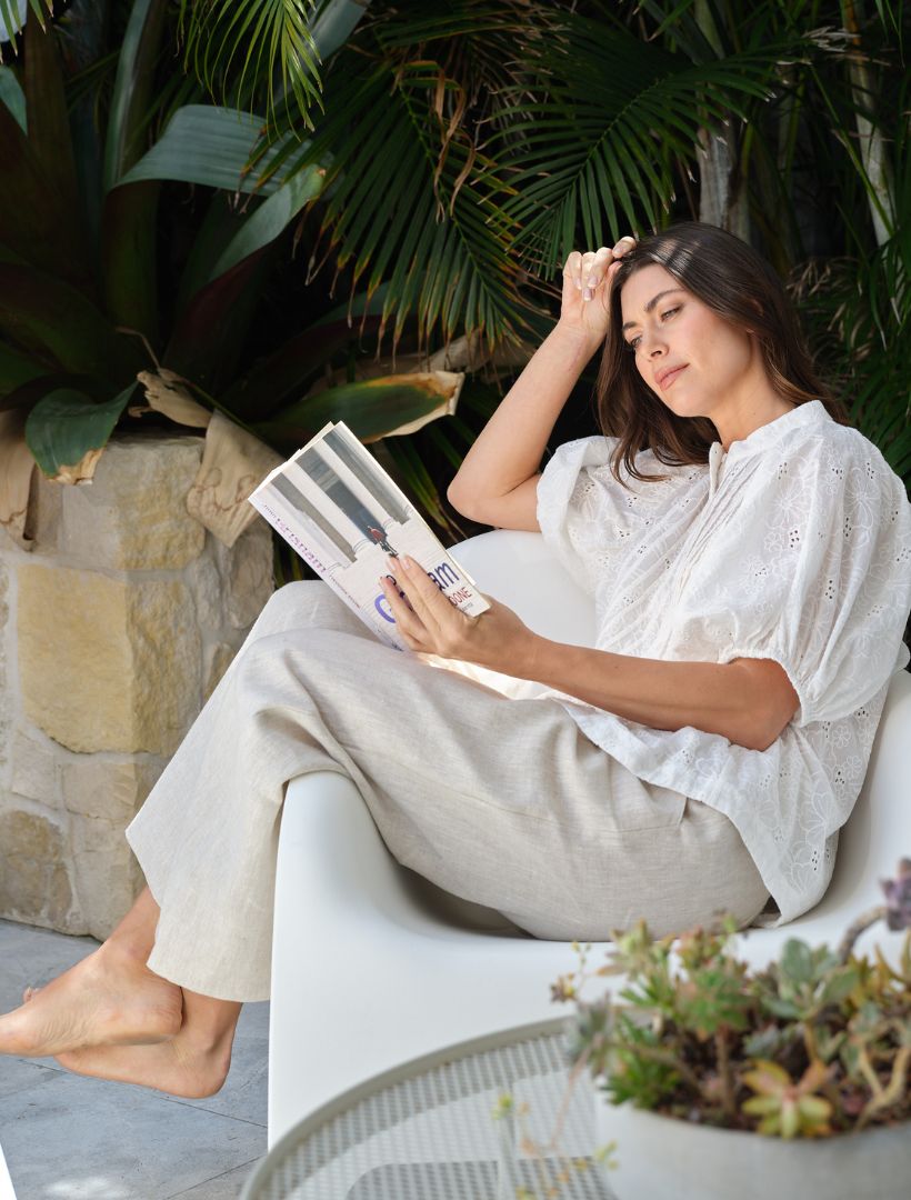 A woman reading wearing Zjoosh beige linen pants