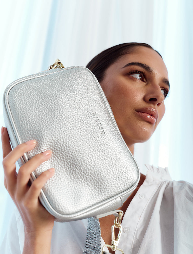 A young woman wearing a silver cross body bag