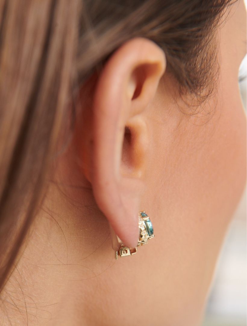 side view of model wearing gold clip on earrings with round blue centre stone and crystal surrounding stones - zjoosh