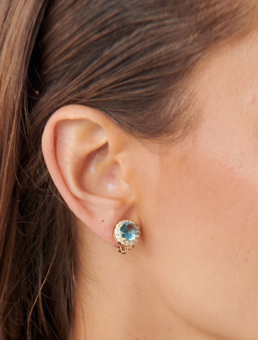 model wearing gold clip on earring. with round light blue centre stone and crystal surrounding stones - zjoosh