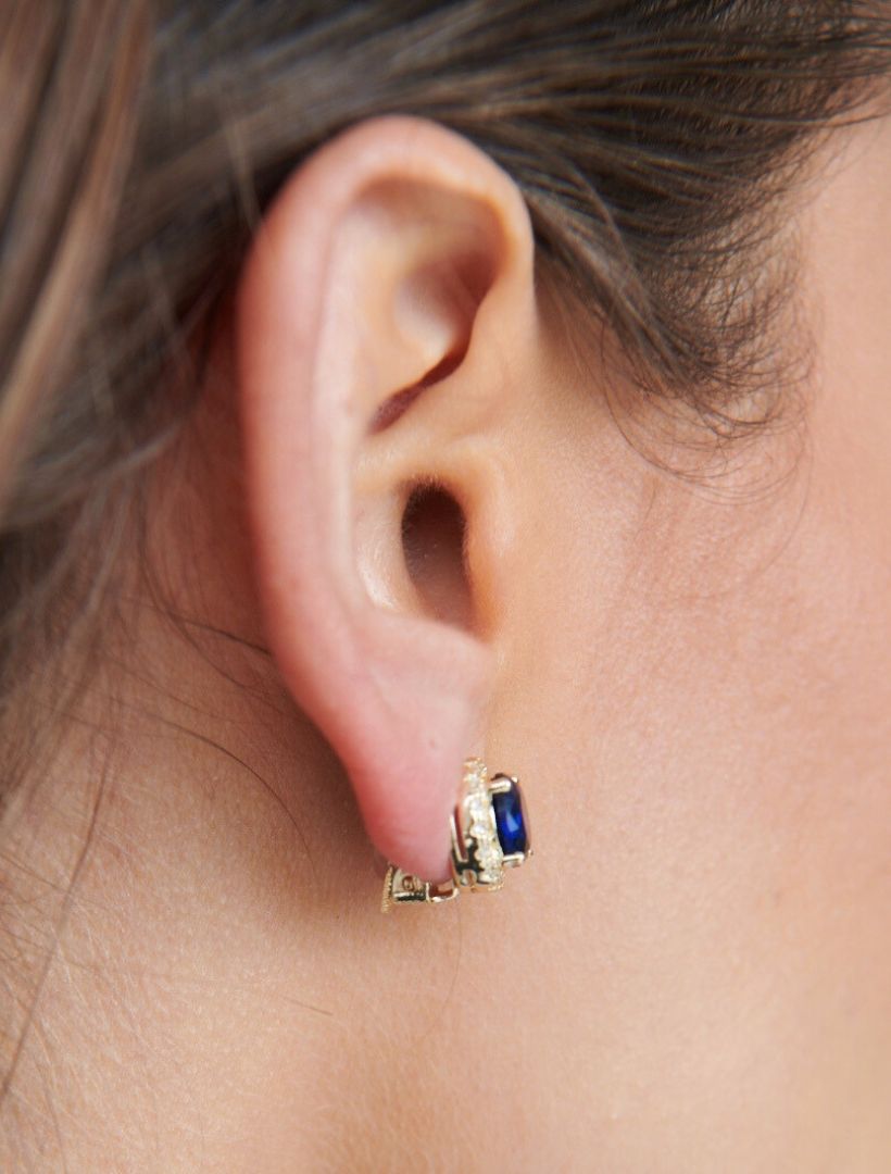 side view of model wearing gold clip on earring with centre small dark blue stone surrounded by white crystals - zjoosh