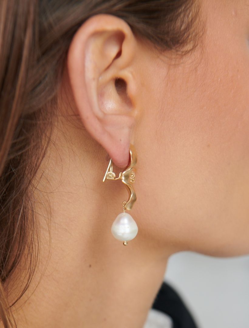 side view of gold clip on earrings, large gold flower with white pearl drop