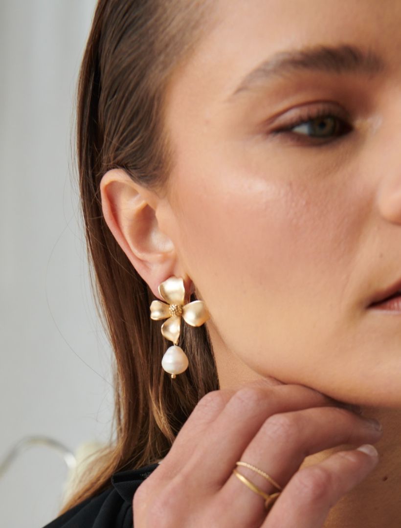 model wearing gold clip on earring, large gold flower with white pearl drop - zjoosh