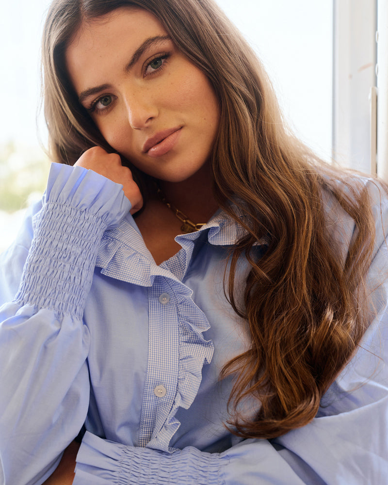 Closeup image of woman in a blue top, new fashion arrivals.